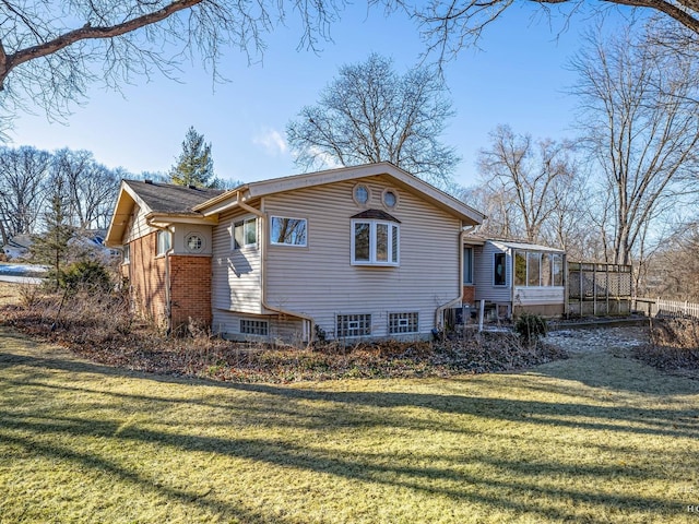 rear view of property featuring brick siding, a lawn, and a sunroom