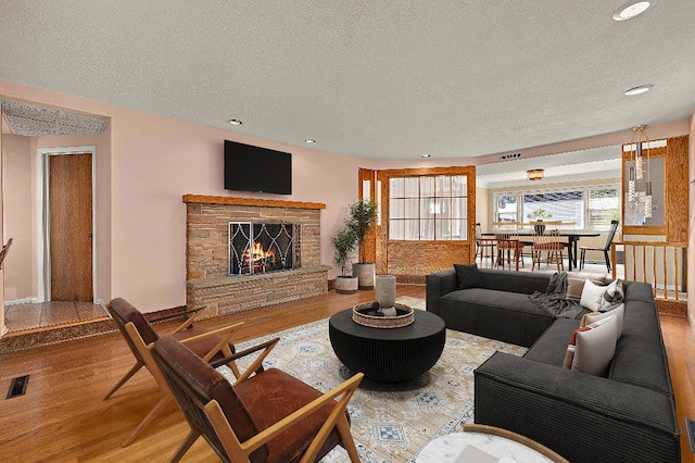 living room with a textured ceiling, recessed lighting, a fireplace, wood finished floors, and visible vents