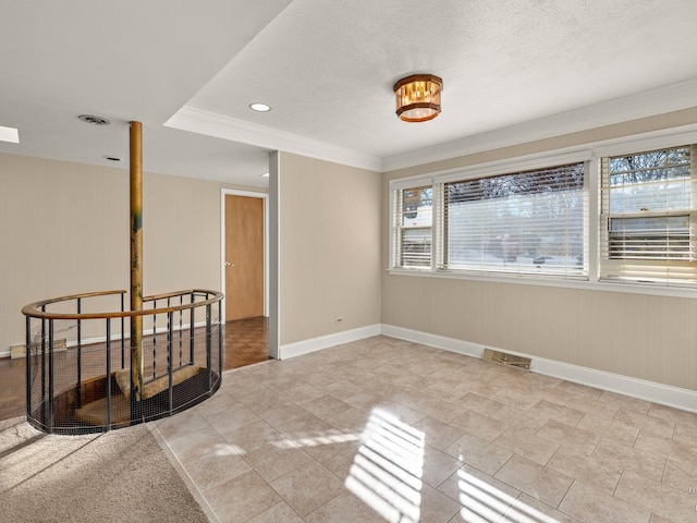 spare room with baseboards, crown molding, visible vents, and a textured ceiling