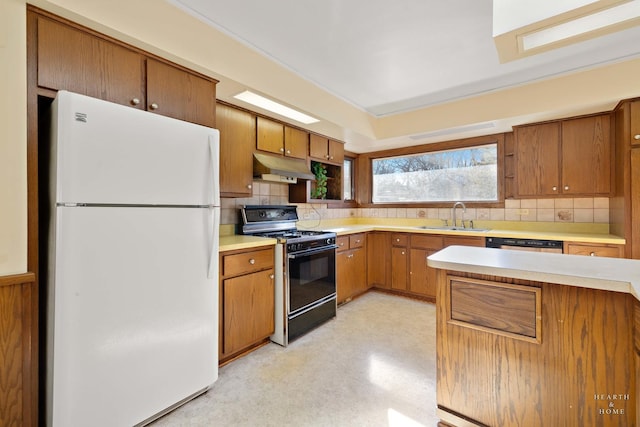 kitchen featuring black gas range, light countertops, a sink, and freestanding refrigerator