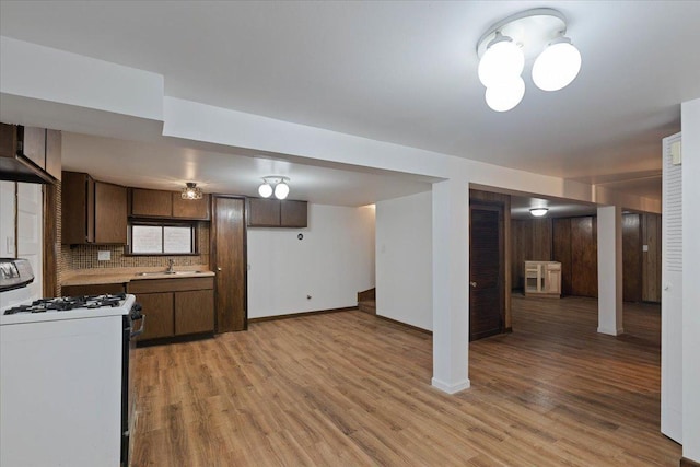 kitchen featuring light countertops, white gas stove, light wood-style floors, and a sink