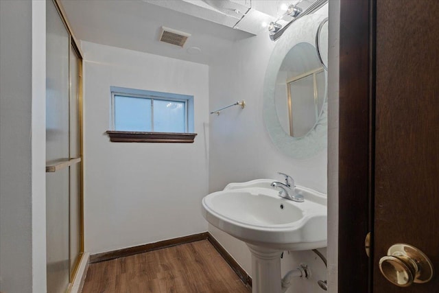 bathroom with a shower with door, visible vents, baseboards, and wood finished floors