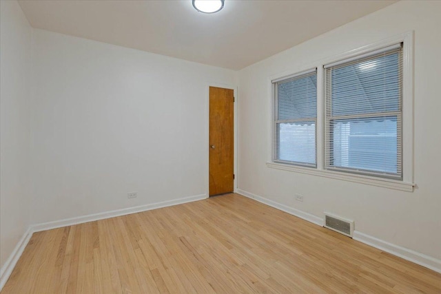 unfurnished room with light wood-type flooring, visible vents, and baseboards