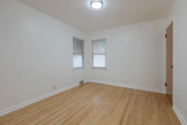 unfurnished room featuring baseboards, visible vents, and light wood finished floors