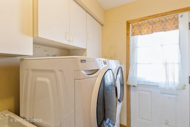 clothes washing area with washer and dryer and cabinet space