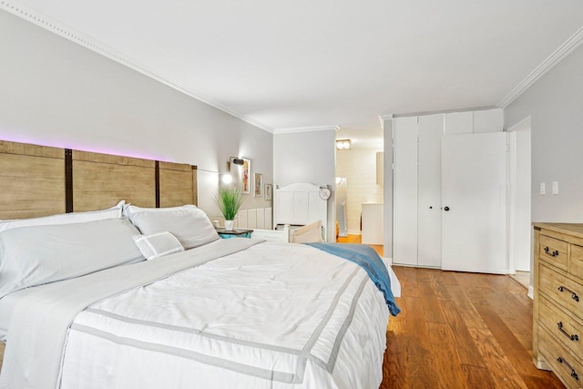 bedroom with crown molding, connected bathroom, and wood finished floors