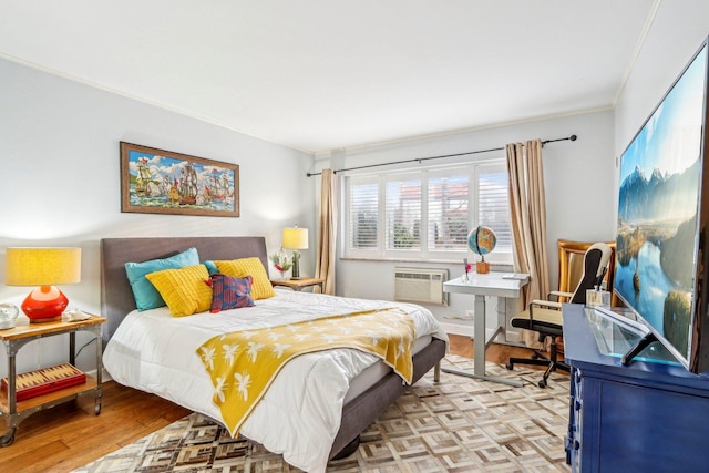 bedroom with light wood-style floors, crown molding, and a wall mounted AC