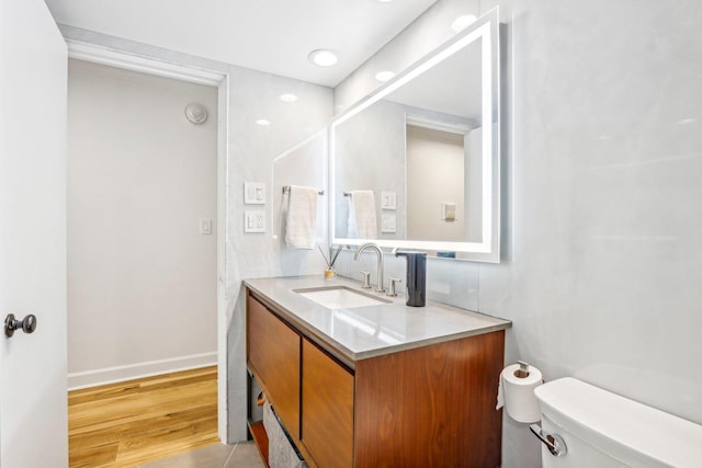 bathroom featuring wood finished floors, vanity, toilet, and baseboards