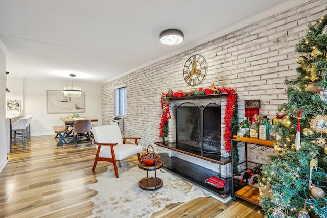 interior space with a fireplace, crown molding, brick wall, and wood finished floors