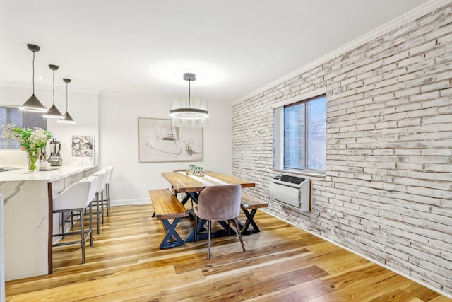 dining area featuring brick wall, light wood-style flooring, crown molding, and a wall mounted AC