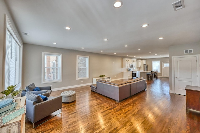 living room with recessed lighting, visible vents, and wood finished floors