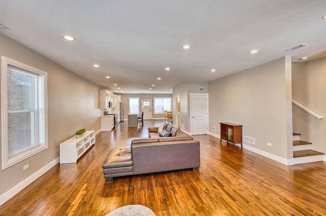 living room featuring dark wood-style floors, recessed lighting, visible vents, and stairs