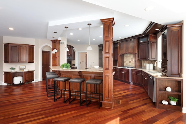 kitchen with dark wood-type flooring, arched walkways, decorative light fixtures, and a sink