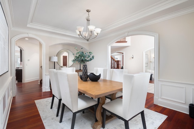 dining area with arched walkways, crown molding, dark wood-style floors, and an inviting chandelier