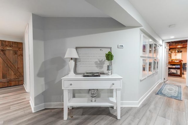 hall featuring light wood-style flooring and baseboards