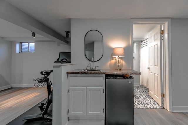 bar featuring light wood-style floors, baseboards, a sink, and freestanding refrigerator