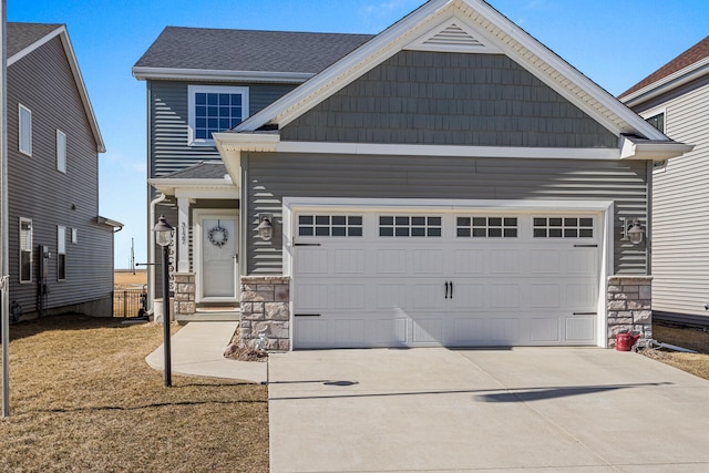 view of front of home featuring an attached garage, stone siding, roof with shingles, and concrete driveway