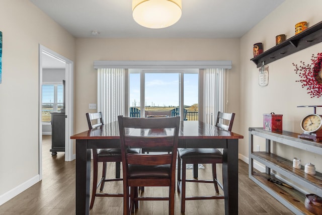 dining room featuring dark wood finished floors, plenty of natural light, and baseboards