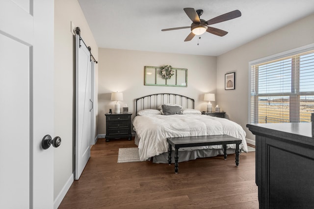 bedroom featuring a ceiling fan, dark wood-style flooring, baseboards, and a barn door