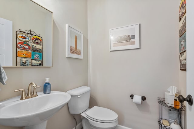 bathroom with a sink, toilet, and baseboards