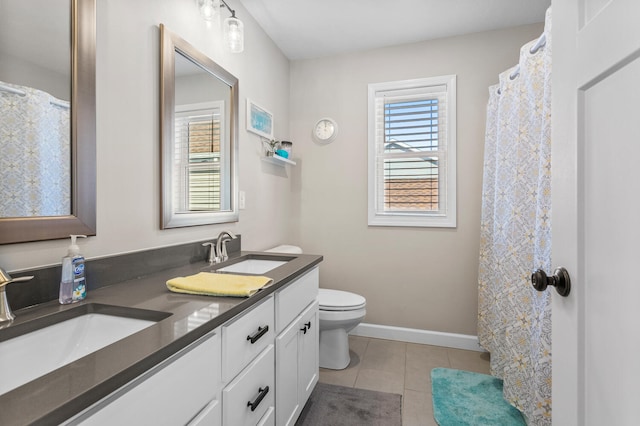 bathroom with baseboards, double vanity, a sink, and tile patterned floors