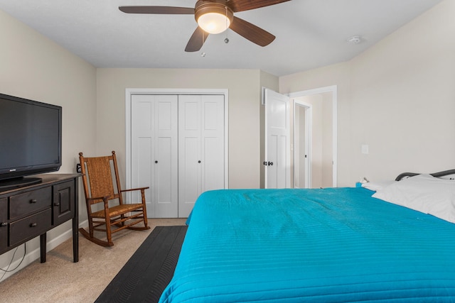 bedroom with a ceiling fan, a closet, light colored carpet, and baseboards