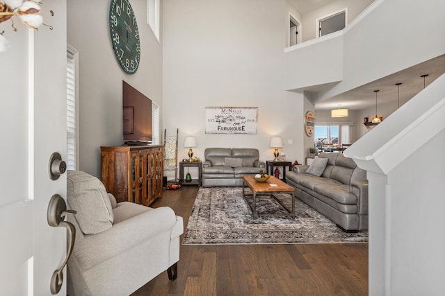 living room featuring a high ceiling and dark wood-style flooring