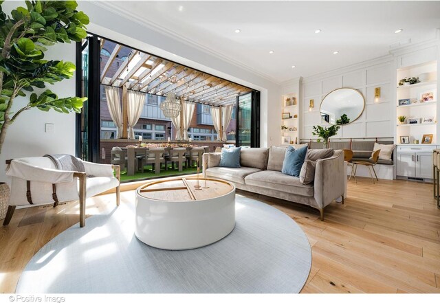 living room featuring ornamental molding, built in shelves, recessed lighting, and light wood-type flooring