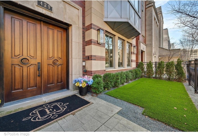property entrance featuring fence and a yard
