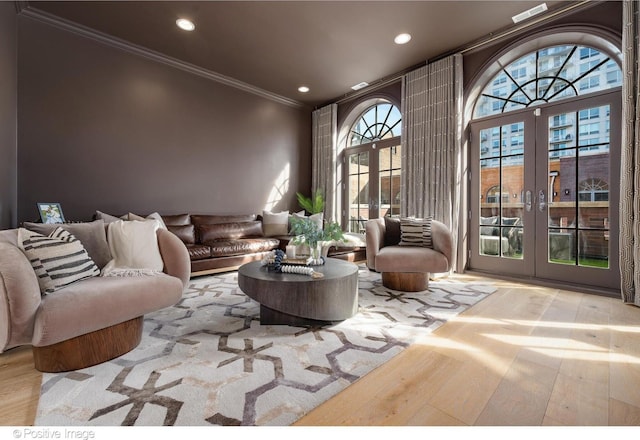 living area with recessed lighting, wood finished floors, ornamental molding, and french doors