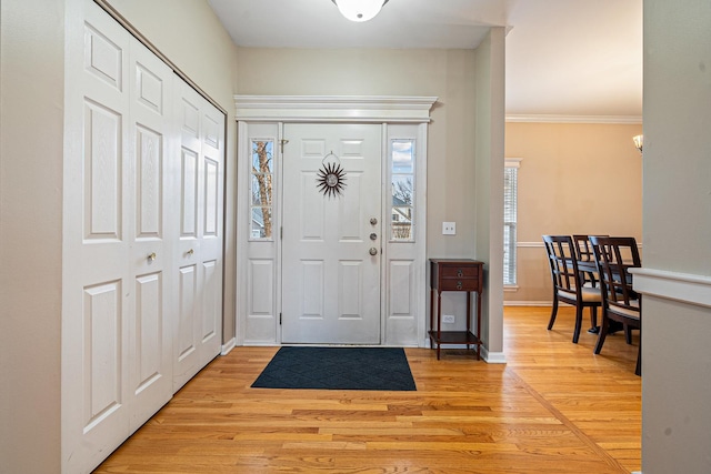 foyer entrance with light wood-type flooring, baseboards, and ornamental molding