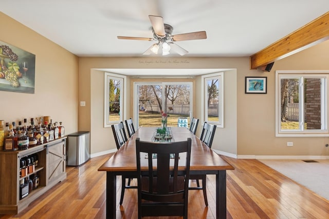 dining room featuring visible vents, light wood-type flooring, beam ceiling, and baseboards