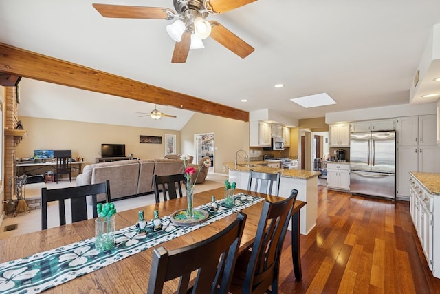 dining space featuring lofted ceiling with skylight, wood finished floors, a ceiling fan, and recessed lighting