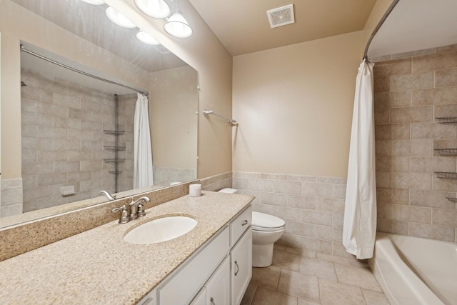 full bathroom featuring tile patterned flooring, toilet, vanity, visible vents, and tile walls