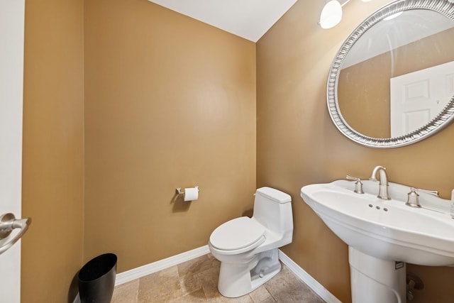 bathroom with a sink, toilet, and baseboards