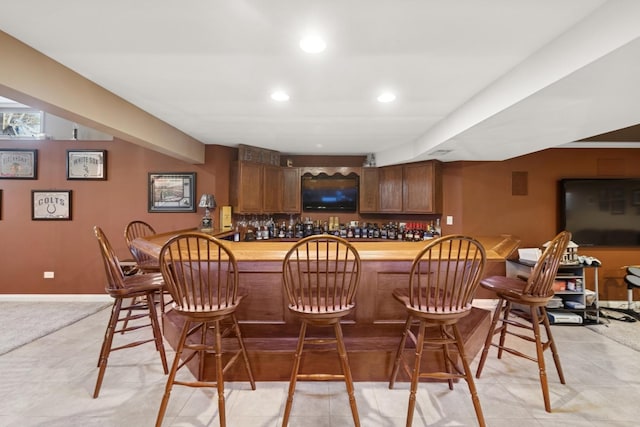 bar featuring recessed lighting, baseboards, and a bar