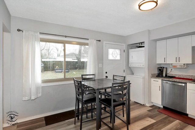 dining space featuring a wealth of natural light, wood finished floors, stacked washer and clothes dryer, and baseboards