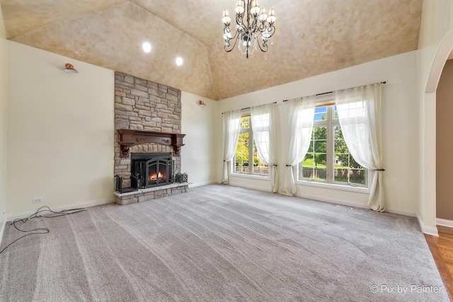 unfurnished living room featuring arched walkways, lofted ceiling, light carpet, a stone fireplace, and baseboards