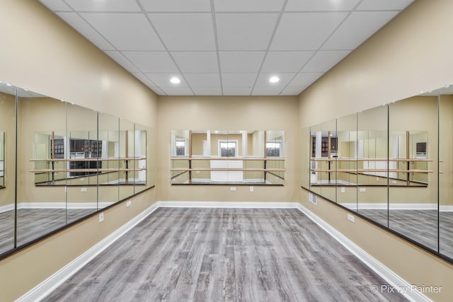 empty room featuring recessed lighting, a drop ceiling, wood finished floors, and baseboards