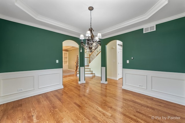 unfurnished dining area featuring visible vents, stairs, arched walkways, and light wood-style flooring