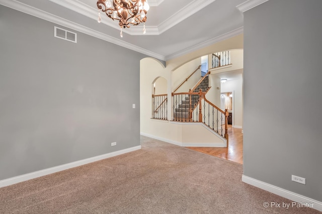 empty room featuring visible vents, stairs, arched walkways, and ornamental molding