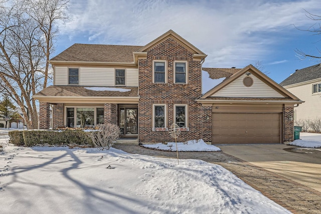 traditional-style house featuring an attached garage, concrete driveway, and brick siding