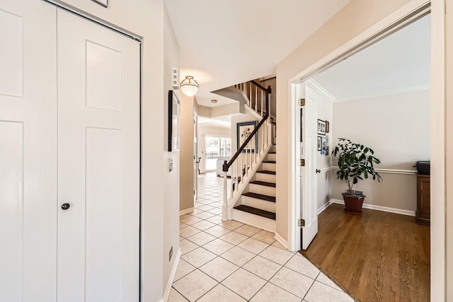 hall with light tile patterned floors, baseboards, stairway, and crown molding