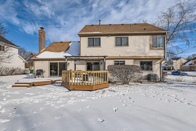 snow covered house with a chimney, a deck, central AC unit, and a pergola