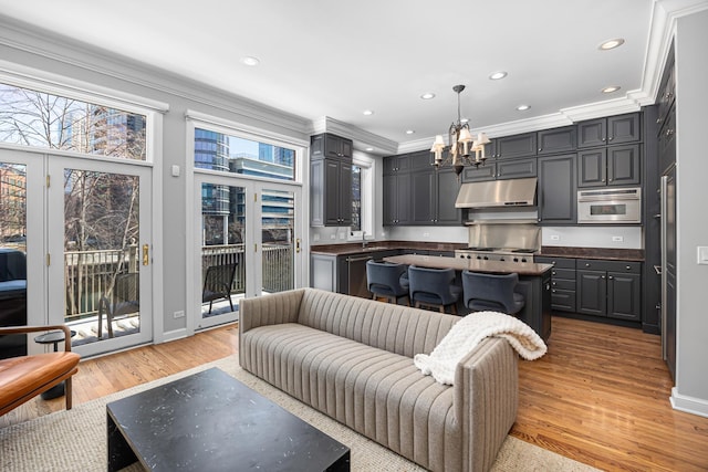 living area with light wood-type flooring, ornamental molding, recessed lighting, an inviting chandelier, and baseboards