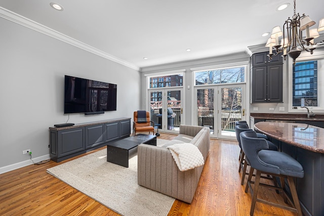 living area featuring baseboards, light wood finished floors, an inviting chandelier, recessed lighting, and ornamental molding