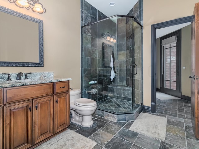 full bathroom featuring toilet, a stall shower, baseboards, and vanity