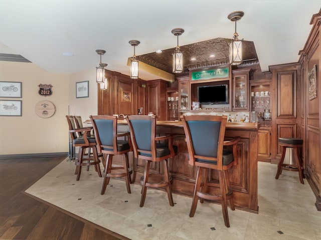 bar with hanging light fixtures, wet bar, and baseboards