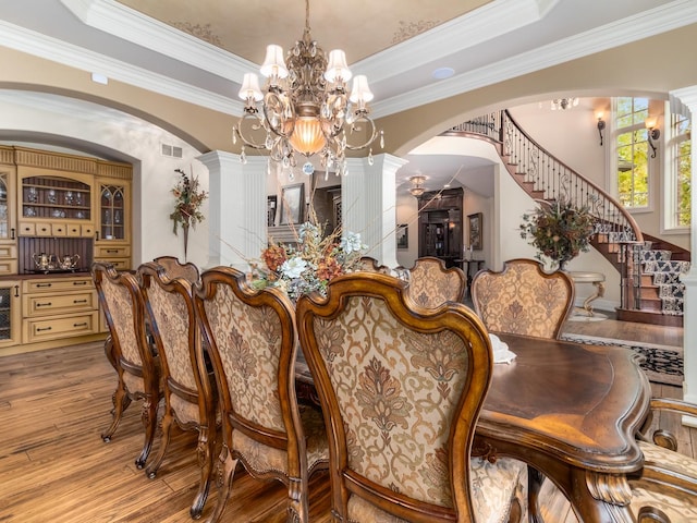 dining area featuring a raised ceiling, visible vents, ornamental molding, wood finished floors, and stairs