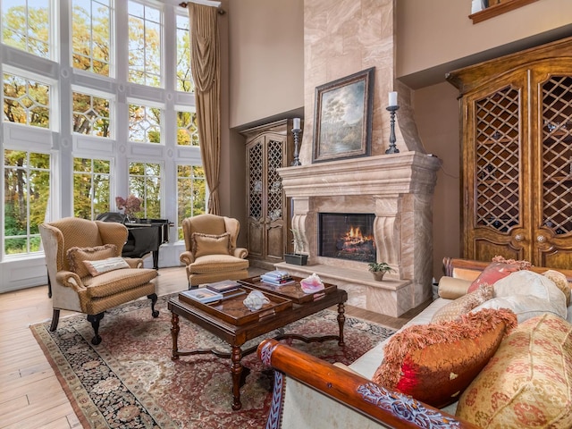 interior space with light wood-style floors, a high end fireplace, and a high ceiling